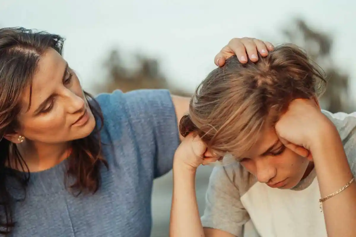 A mother offers support to her discouraged teenager son, portraying love and understanding.