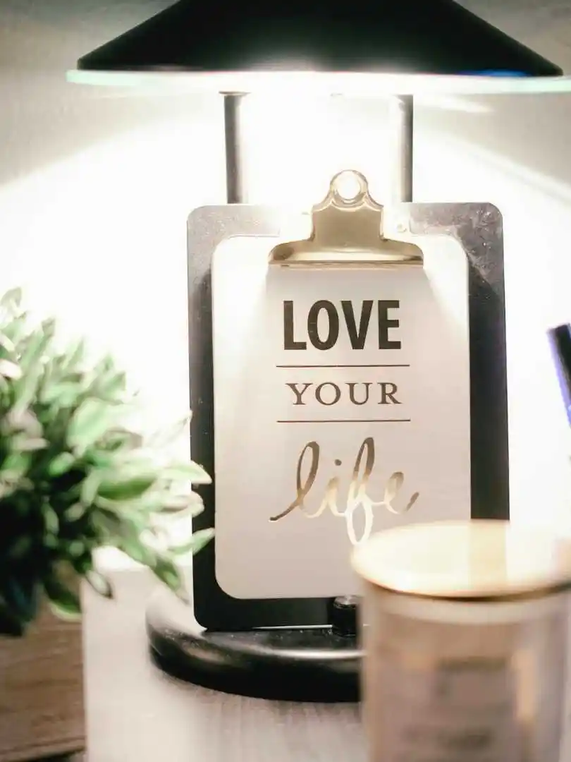A warmly lit desk setup featuring a lamp, inspirational clipboard, and decor for a cozy ambiance.
